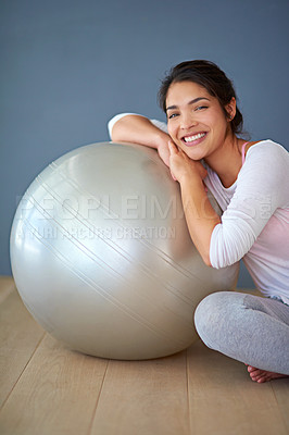 Buy stock photo Cropped shot of a sporty young woman leaning against a pilates ball