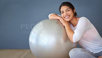 Buy stock photo Cropped shot of a sporty young woman leaning on a pilates ball against a grey background