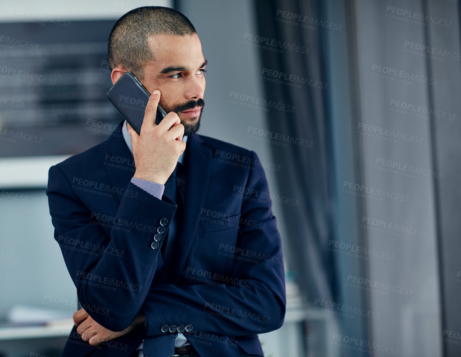 Buy stock photo Shot of a young businessman talking on a cellphone in his office