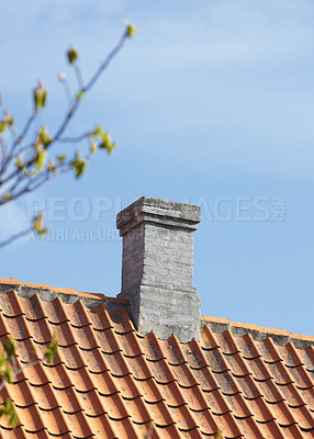 Buy stock photo Grey brick chimney designed on slate roof of house building outside against blue sky background. Construction of exterior architecture of escape chute built on rooftop for fireplace smoke and heat