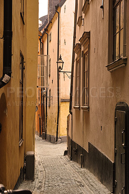 Buy stock photo View of an empty, cobble street, alley between city buildings abroad in Stockholm, Gamla Stan. Narrow cobbled stone road in an old small overseas village. Exploring town, enjoying holiday and vacation