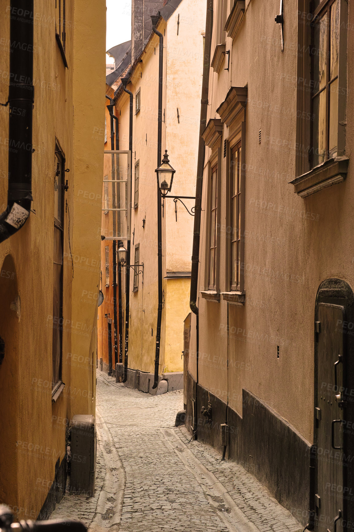 Buy stock photo View of an empty, cobble street, alley between city buildings abroad in Stockholm, Gamla Stan. Narrow cobbled stone road in an old small overseas village. Exploring town, enjoying holiday and vacation