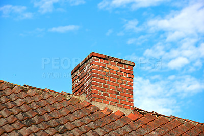 Buy stock photo Red brick chimney designed on slate roof of a house building outside with cloudy blue sky background and copyspace. Construction of exterior escape chute built on rooftop for fireplace smoke and heat