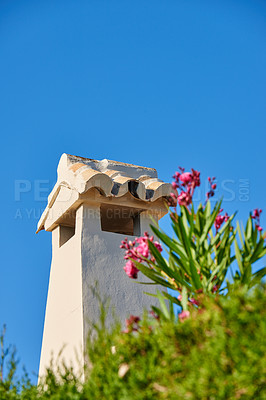 Buy stock photo Chimney tower designed roof house building outside against blue sky background and green plant foreground. Construction of exterior architecture of chute built on rooftop for fireplace smoke and heat