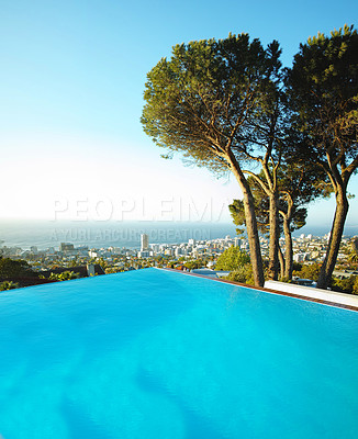 Buy stock photo Scenic view of infinity swimming pool overlooking city and ocean in background. Luxury outdoor blue pool on a deck, patio, veranda or rooftop on a condo, home or hotel. Cityscape and skyline with sea