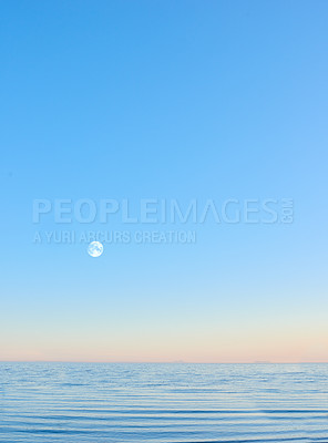 Buy stock photo Scenic view of an infinity pool with copyspace and the moon rising over a hazy horizon at sunset. Seascape of a blue sky on an empty ocean and sea at dusk. Evening over a luxury eternity swimming pool