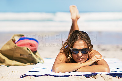Buy stock photo Portrait of a beautiful young woman lying on a towel at the beach