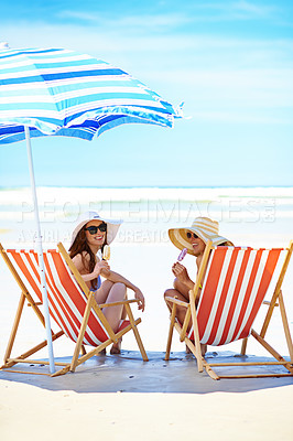 Buy stock photo Portrait of two beautiful young women eating an ice cream at the beach