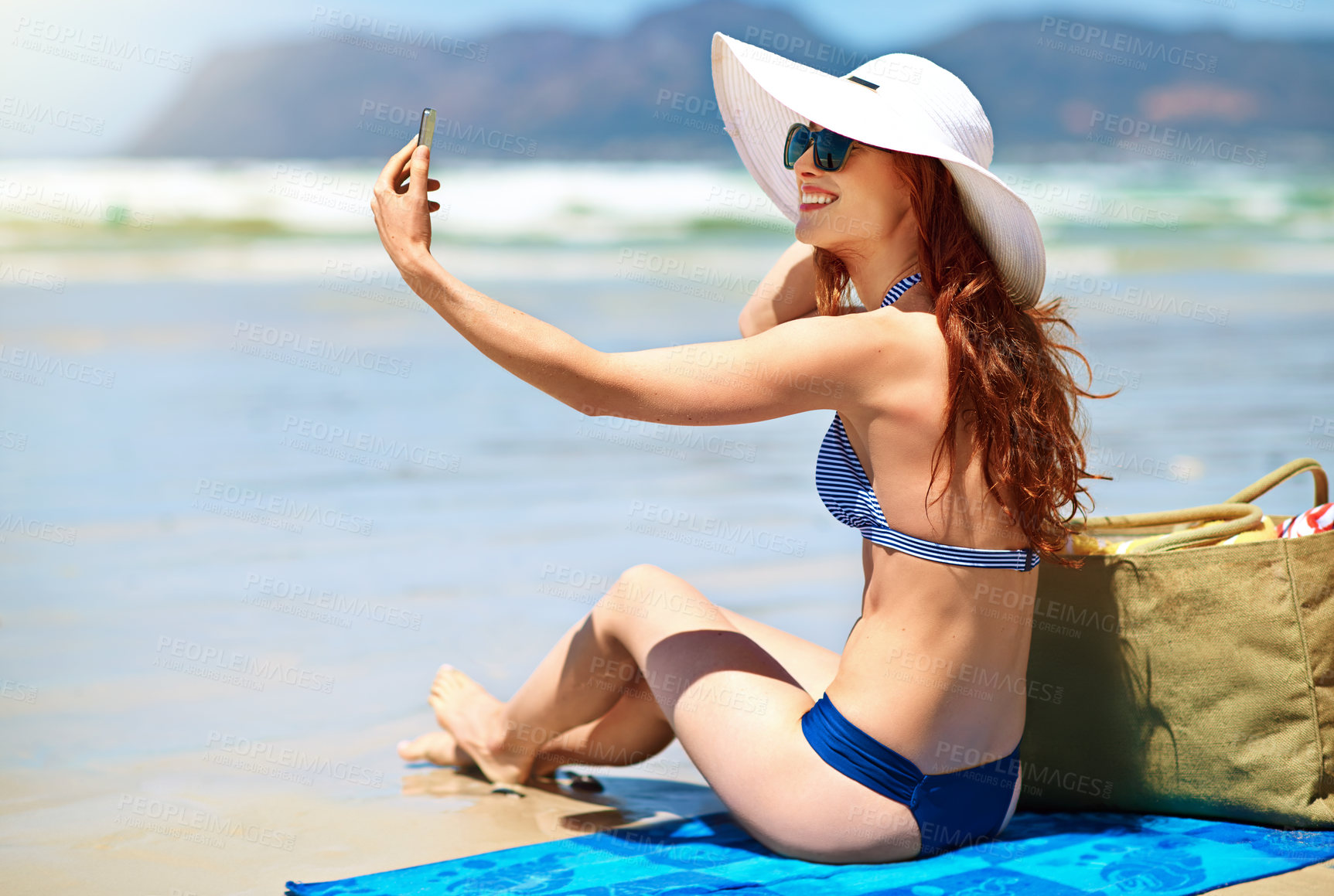 Buy stock photo Woman, happy and sunglasses on beach for selfie, tanning and travel in summer. Tourist, towel and smile on sand for photography, holiday and live streaming at ocean with peace and calm in Mauritius