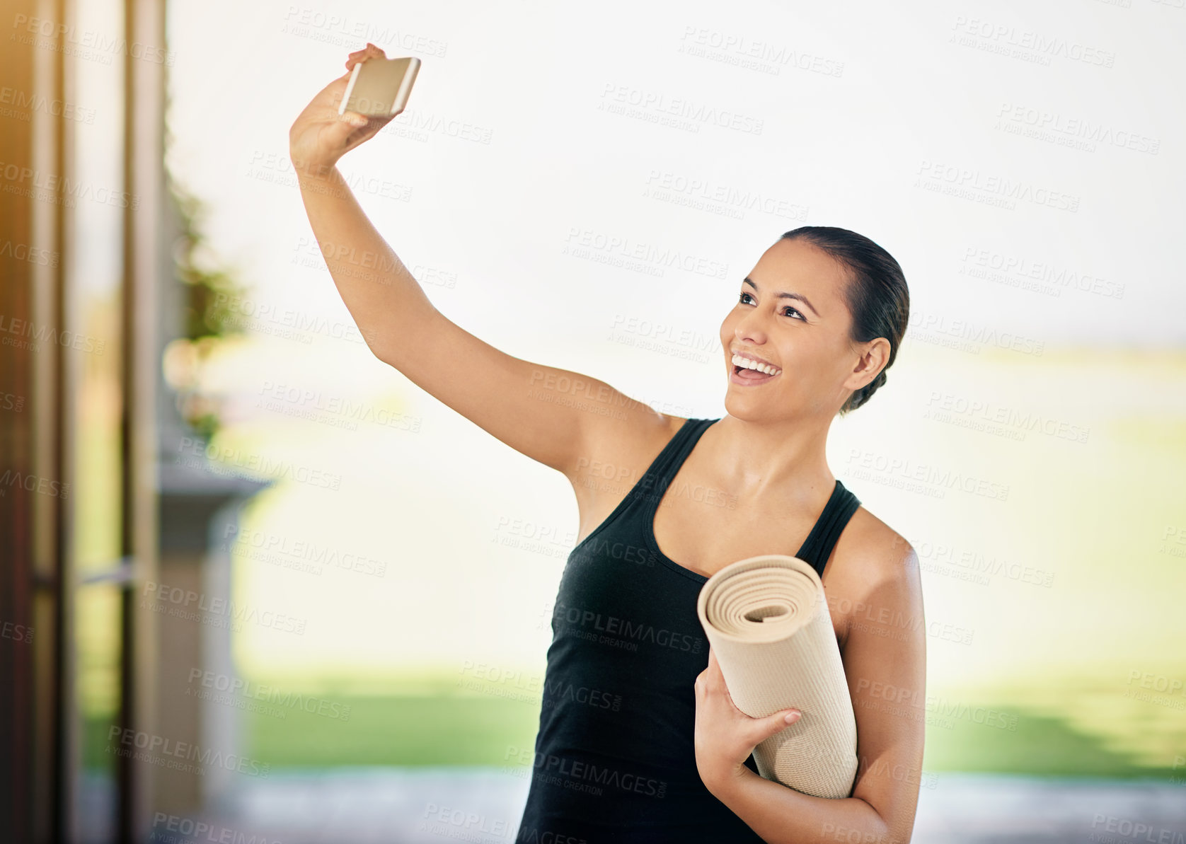 Buy stock photo Cropped shot of a young woman taking a selfie while carrying her yoga mat
