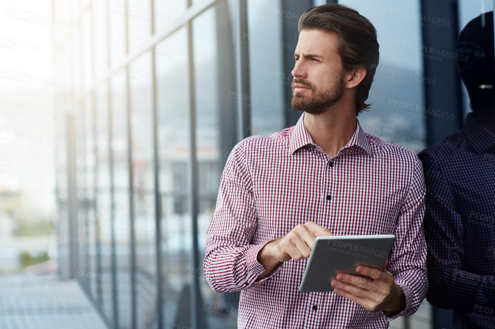 Buy stock photo Shot of a young businessman using a digital tablet outside of an office building