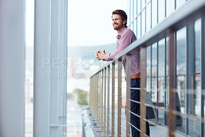 Buy stock photo Shot of a happy young businessman standing on the balcony of an office building
