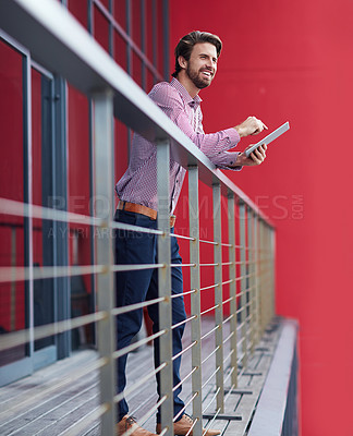 Buy stock photo Shot of a young businessman using a digital tablet on the balcony of an office building
