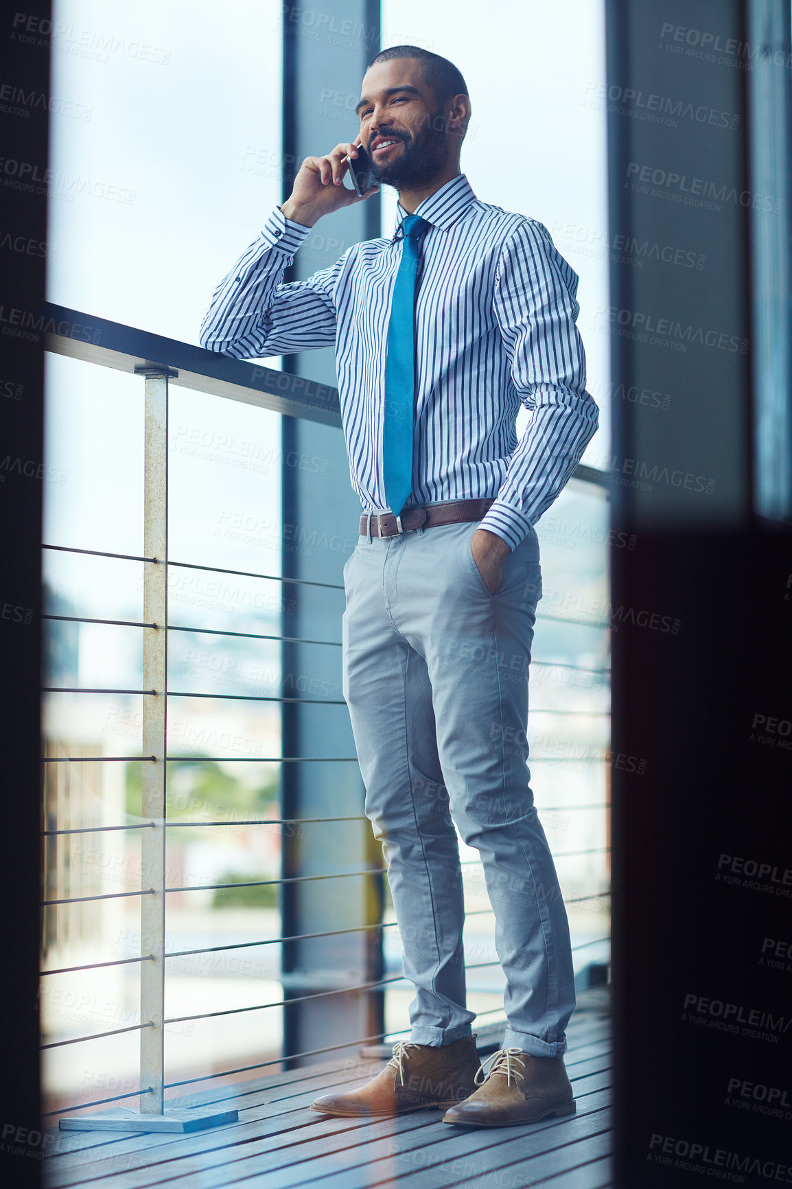 Buy stock photo Shot of a young businessman talking on a phone at the office
