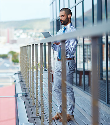 Buy stock photo Shot of a young businessman using a digital tablet outside of an office building