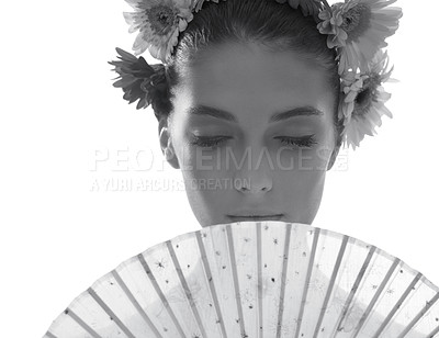Buy stock photo Black and white shot of a beautiful young woman wearing a crown of flowers while holding a fan in front of her face