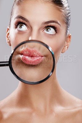 Buy stock photo Studio shot of a beautiful woman with a magnifying glass in front of her mouth