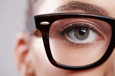 Buy stock photo Closeup studio portrait of a young woman wearing glasses against a gray background