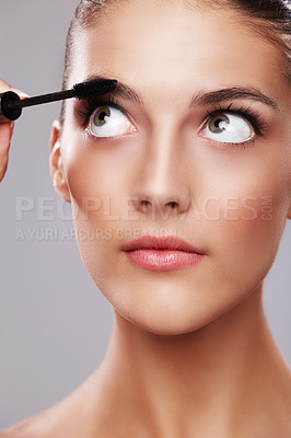 Buy stock photo Studio shot of a beautiful young woman applying makeup  against a gray background