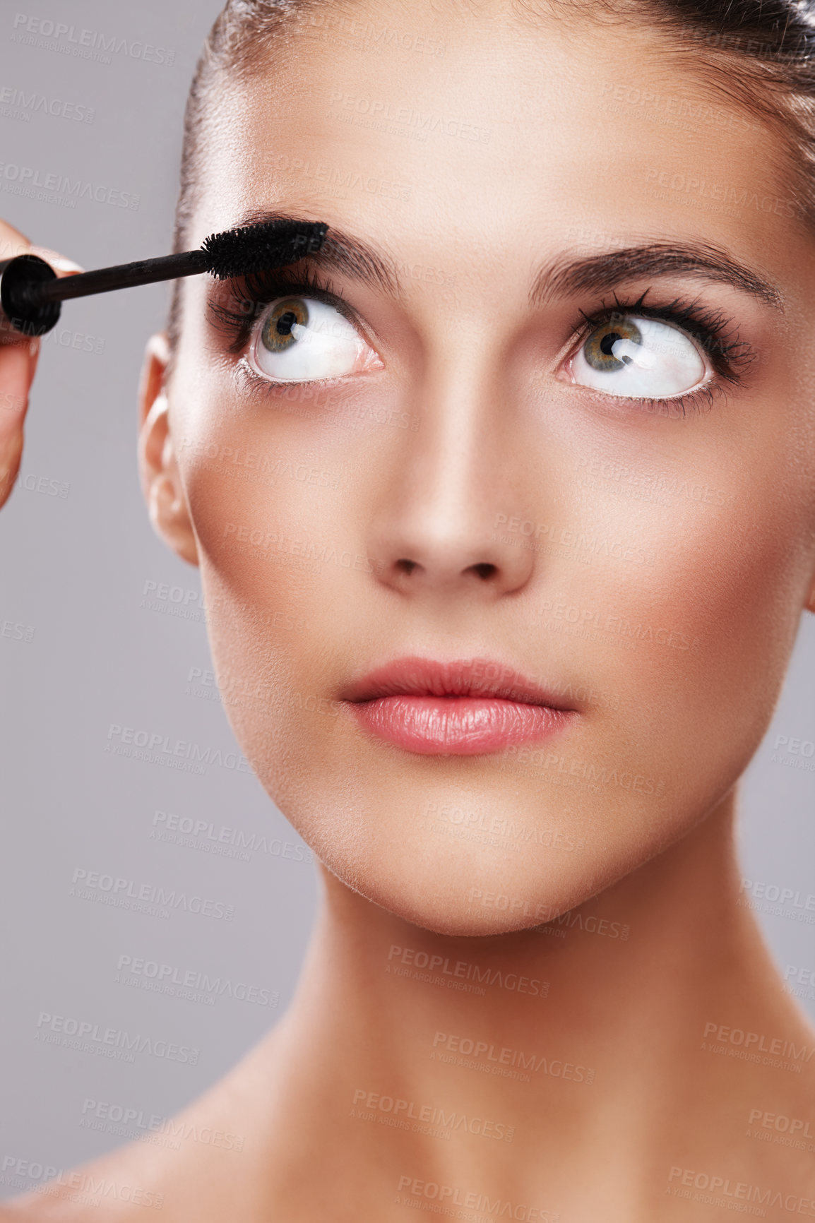 Buy stock photo Studio shot of a beautiful young woman applying makeup  against a gray background