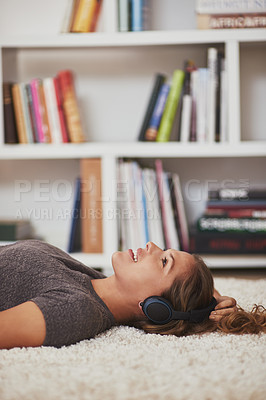 Buy stock photo Shot of a young woman relaxing at home and listening to music