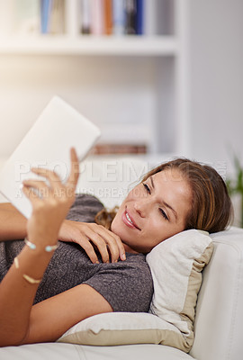 Buy stock photo Shot of a young woman relaxing on the sofa with a digital tablet at home