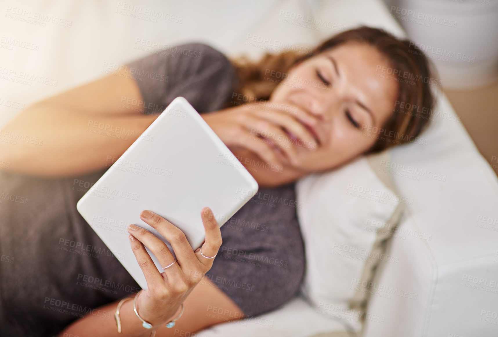 Buy stock photo Shot of a young woman relaxing on the sofa with a digital tablet at home