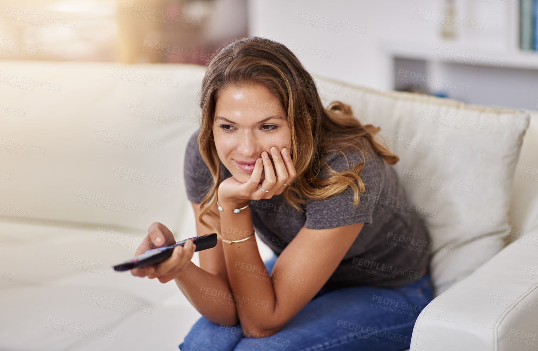 Buy stock photo Shot of a young woman spending a relaxing weekend at home watching tv