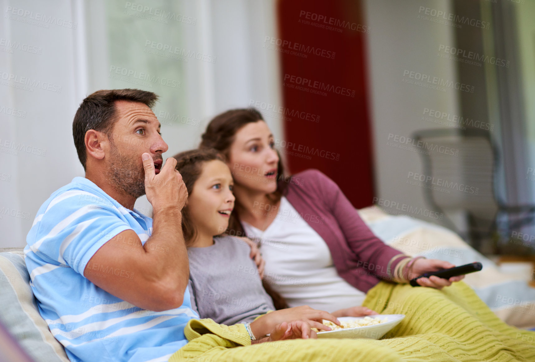 Buy stock photo Cropped shot of a family watching a movie on the sofa