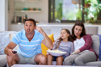Buy stock photo Cropped shot of a man watching sports on the TV while is family sits bored in the background