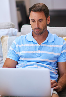 Buy stock photo Cropped shot of a mature man using his laptop while sitting on the sofa