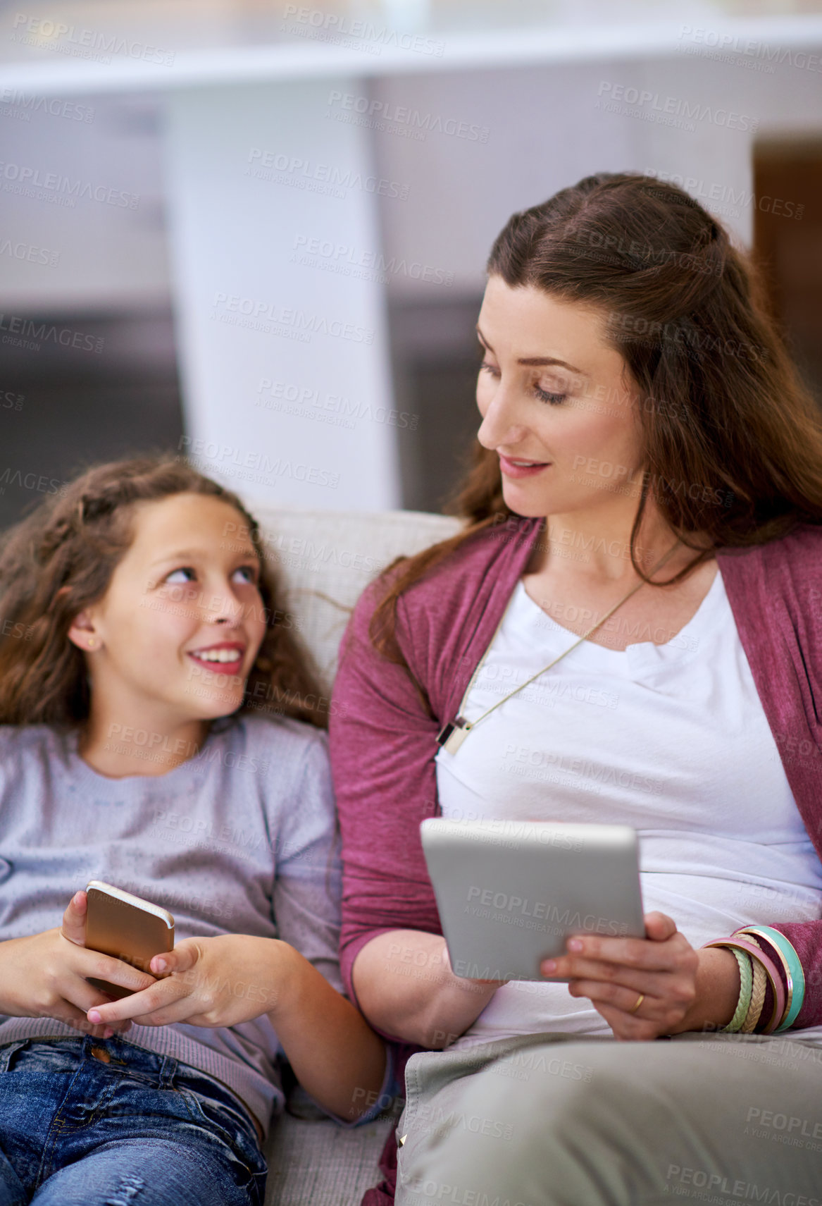 Buy stock photo Cropped shot of a young girll and her mother sitting on the sofa and using their smart devices