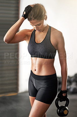 Buy stock photo Cropped shot of a young woman working out with a kettle bell at the gym