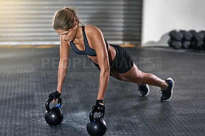 Buy stock photo Full length shot of a young woman working out with kettle bells at the gym