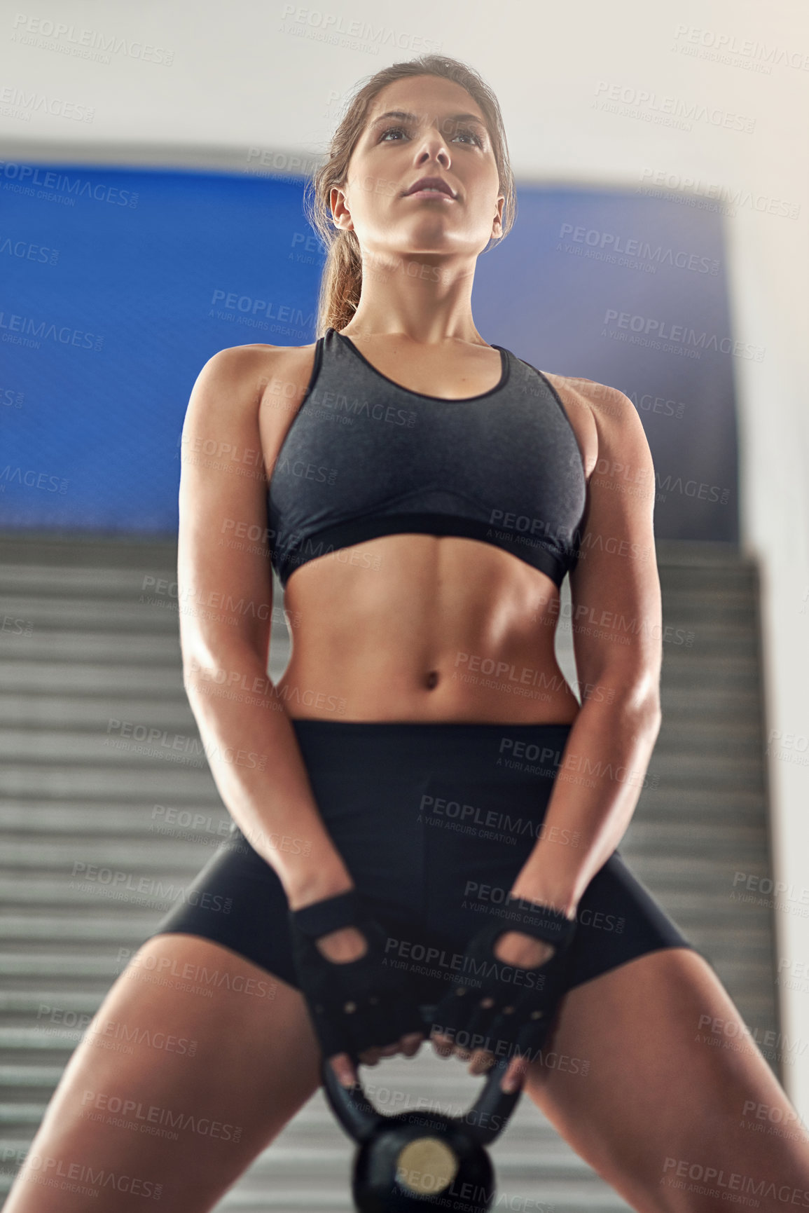 Buy stock photo Cropped shot of a young woman working out with a kettle bell at the gym