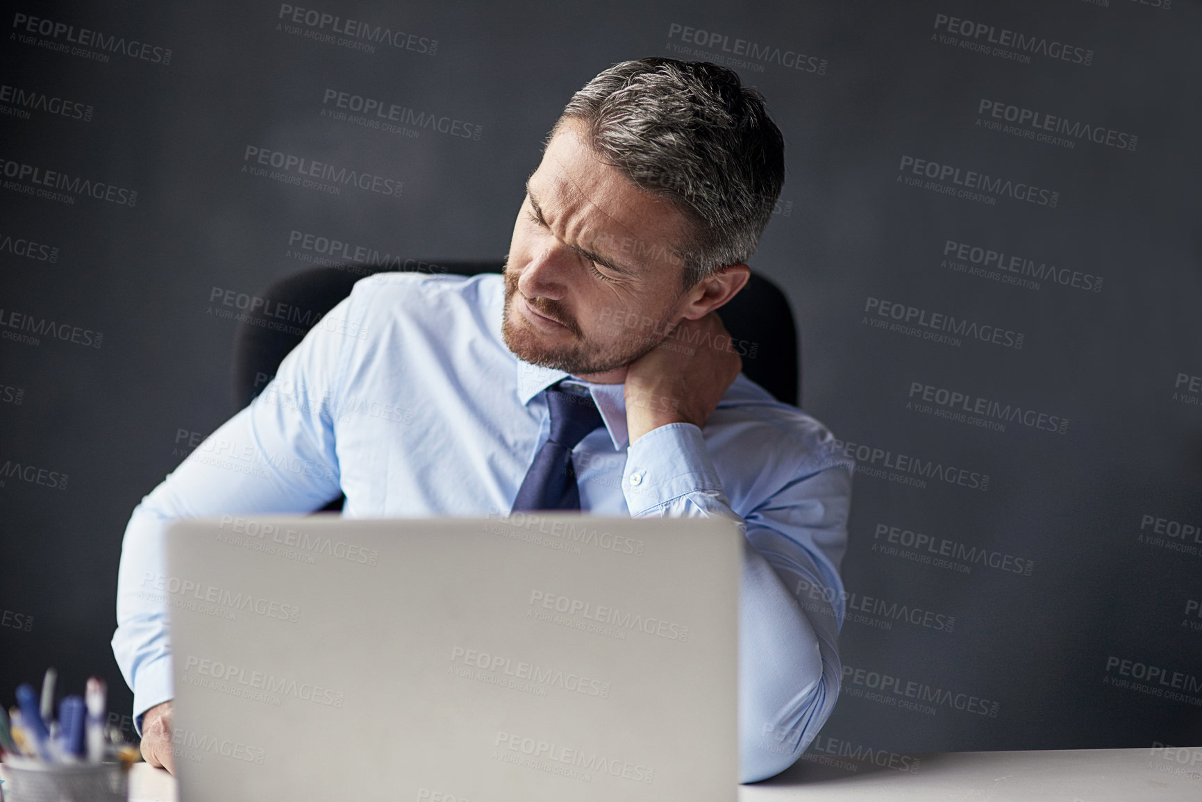 Buy stock photo Cropped shot of a mature businessman running his neck anxiously while working in his office