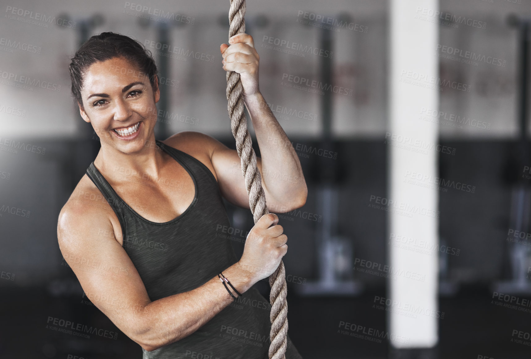 Buy stock photo Cropped portrait of a young woman climbing a rope at the gym