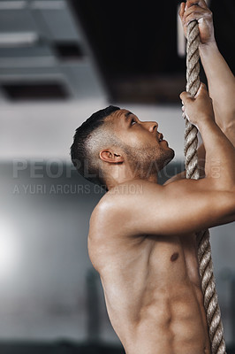 Buy stock photo Cropped shot of a young man climbing a rope at the gym