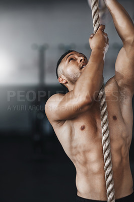 Buy stock photo Cropped shot of a young man climbing a rope at the gym