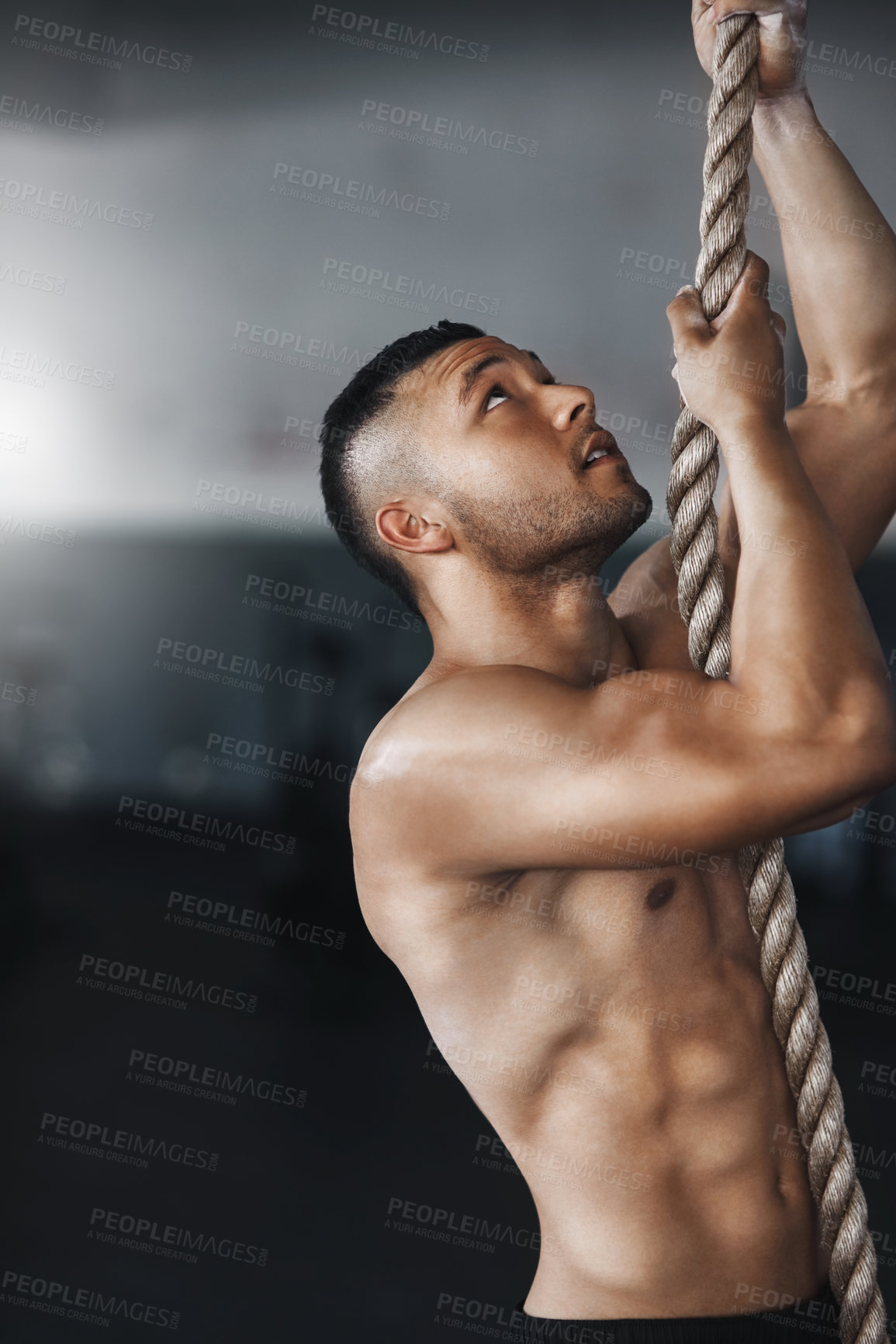 Buy stock photo Man, rope climbing and fitness in gym for health or cardio, exercise challenge with body strength. Male athlete, power workout and commitment to wellness or triathlon, sports club with training