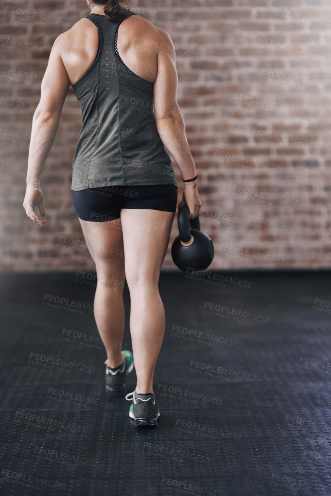 Buy stock photo Rearview shot of a young woman working out in the gym