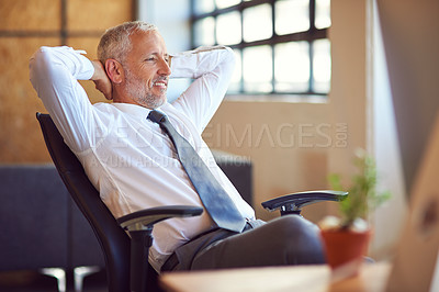 Buy stock photo Shot of a mature businessman relaxing at his desk in the office