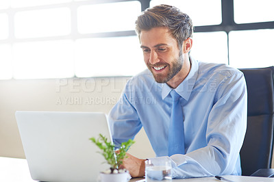 Buy stock photo Shot of a young businessman using a laptop in an office