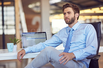 Buy stock photo Shot of a young businessman sitting at his desk in an office