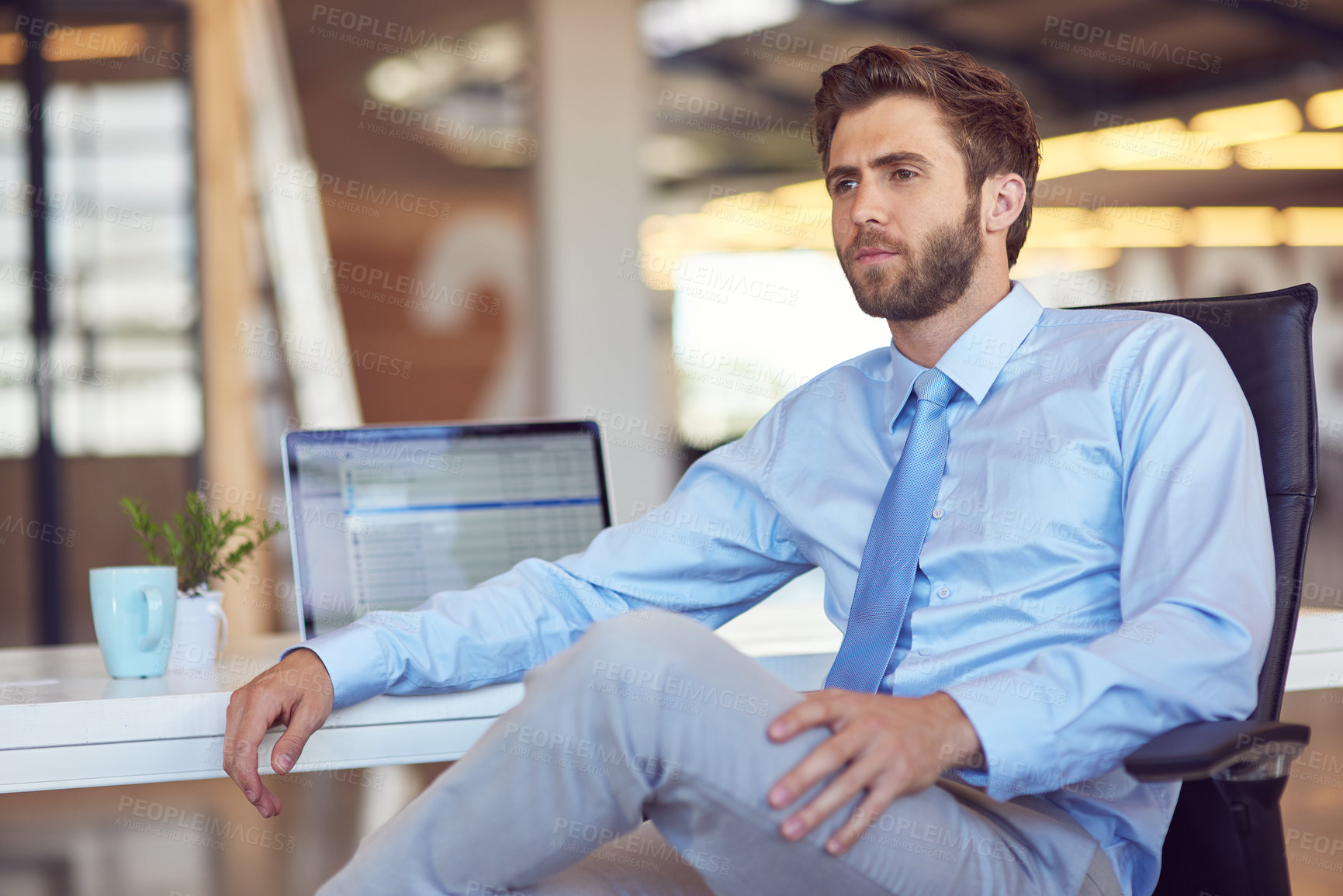 Buy stock photo Shot of a young businessman sitting at his desk in an office