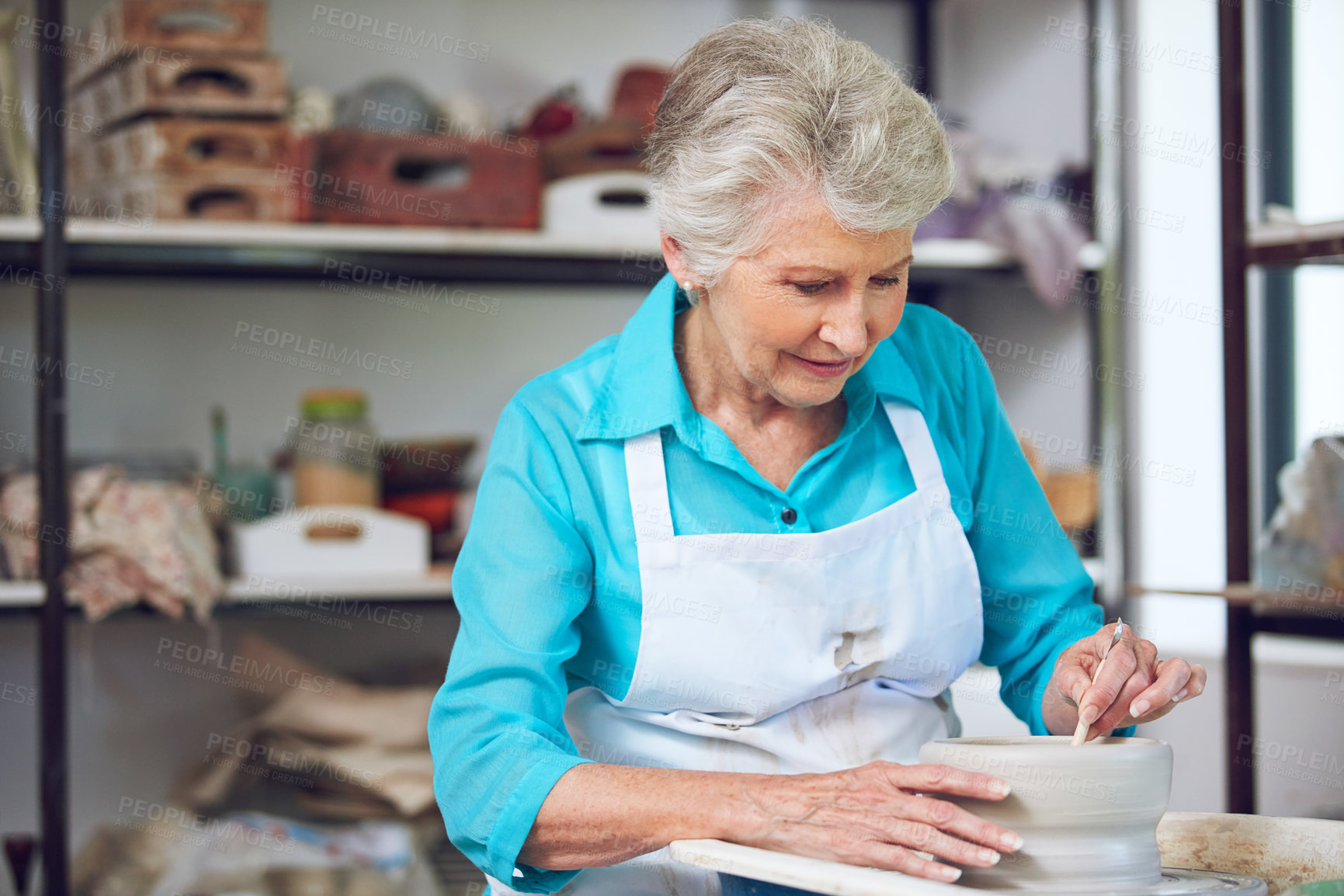 Buy stock photo Shot of a senior woman making a ceramic pot in a workshop