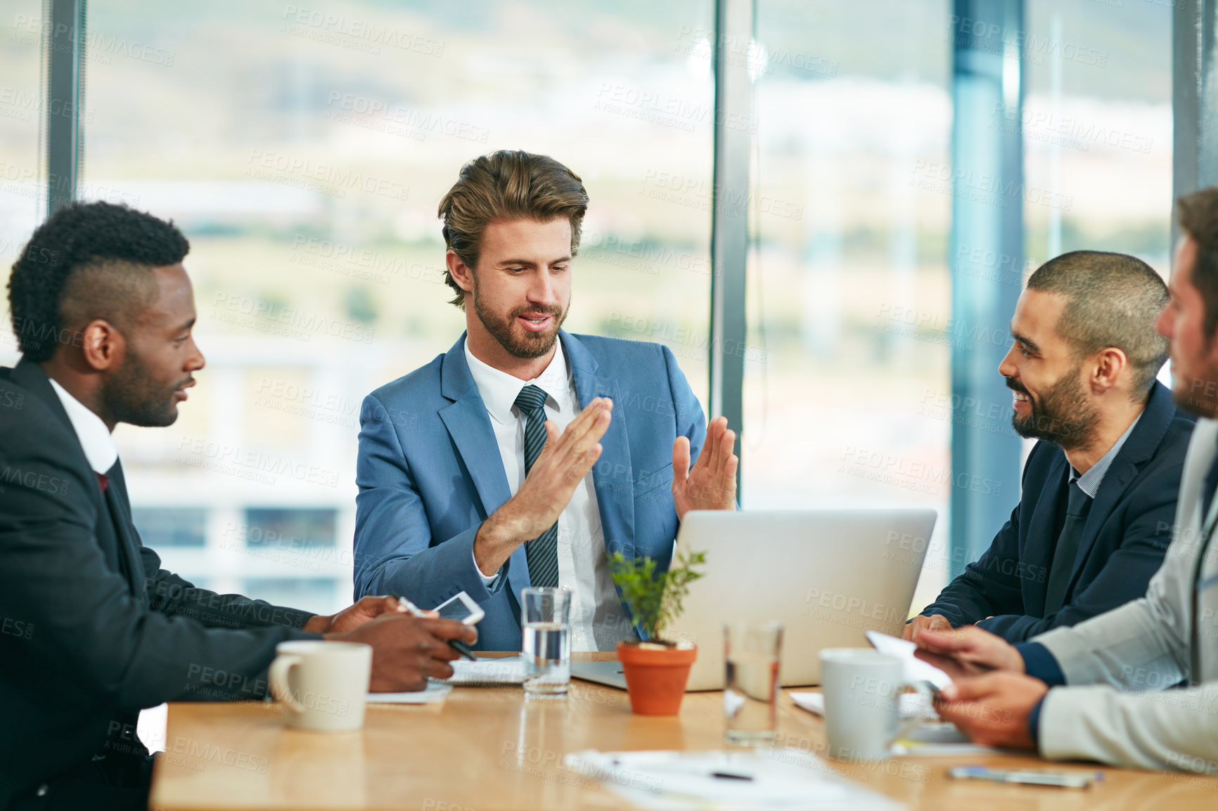 Buy stock photo Shot of a team of colleagues having a meeting around a laptop in a modern office