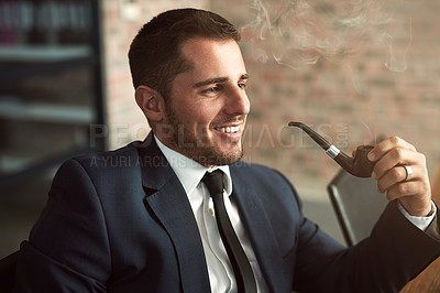 Buy stock photo Shot of a stylish businessman smoking a pipe in the office