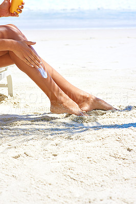 Buy stock photo Cropped shot of a young woman applying suntan lotion while relaxing at the beach