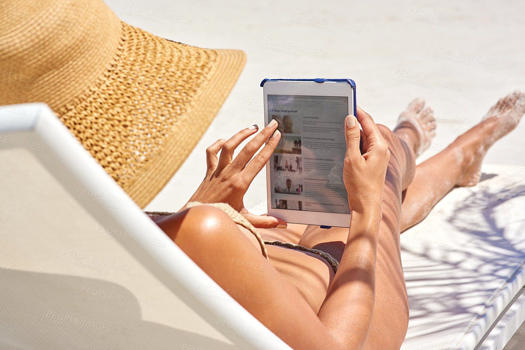 Buy stock photo Cropped shot of a young woman using her tablet while relaxing at the beach